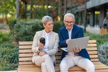 Business colleagues collaborating on laptop during outdoor break