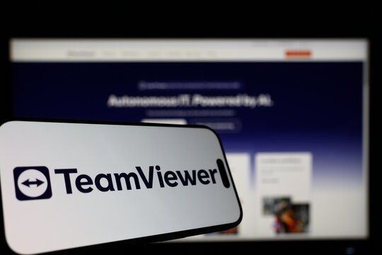 Kiel, Germany - 01-12-2026: Smartphone displaying TeamViewer logo in front of the company website on a monitor