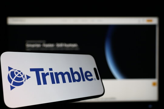 Kiel, Germany - 01-12-2026: Smartphone displaying Trimble logo in front of the company website on a monitor