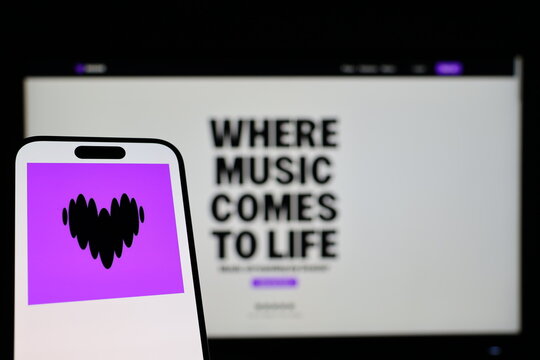 Kiel, Germany - 01-12-2026: Smartphone displaying Deezer logo in front of the company website on a monitor