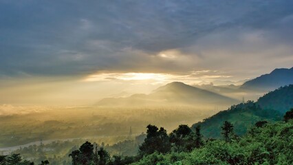 Golden mist over forested hills, sunrise illuminating Gelephu Mindful City in Bhutan