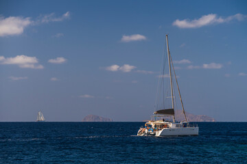 Fototapeta premium Catamaran sailing on open sea under blue sky with distant horizon