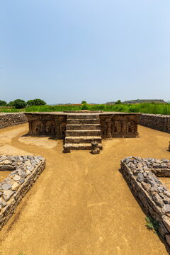 View of a stone structure with steps and intricate carvings stands serenely under a clear sky, radiating an ancient aura, Taxila, Punjab, Pakistan.