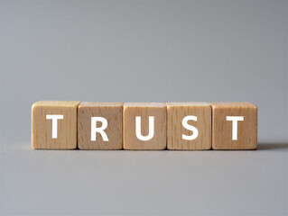 Wooden blocks spelling out trust on a gray surface  concept of faith and reliability