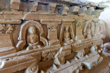 View of weathered stone carvings of Buddha figures in meditative poses, adorned with intricate architectural details, revealing the rich history, Taxila, Khyber Pakhtunkhwa, Pakistan.