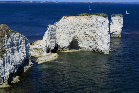 Landscape photo with a view of the chalk cliffs of Old Harry Rocks and sailboats in the background at Studland Bay in the south of the UK