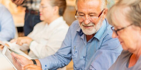 Old people using tablets in a group setting. Senior technology use, digital learning, and...