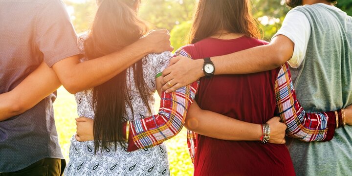 Group of diverse friends embracing outdoors, arms around each other, showing unity and friendship. Diverse Indian group of friends enjoying togetherness, arms around each other