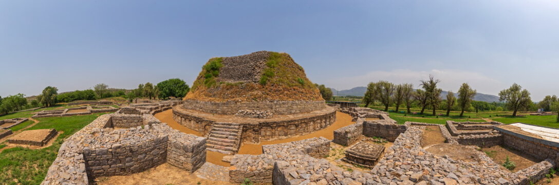 View of the ancient, weathered stone stupa rises majestically under a clear sky amidst the ruins, a testament to history, Taxila, Punjab, Pakistan. - Powered by Adobe