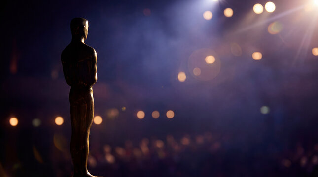Golden trophy on gala stage. Dramatic spotlight bokeh shows trophy silhouette at academy awards night, trophy symbol of success for film industry ceremony, awards season concept, premium mood