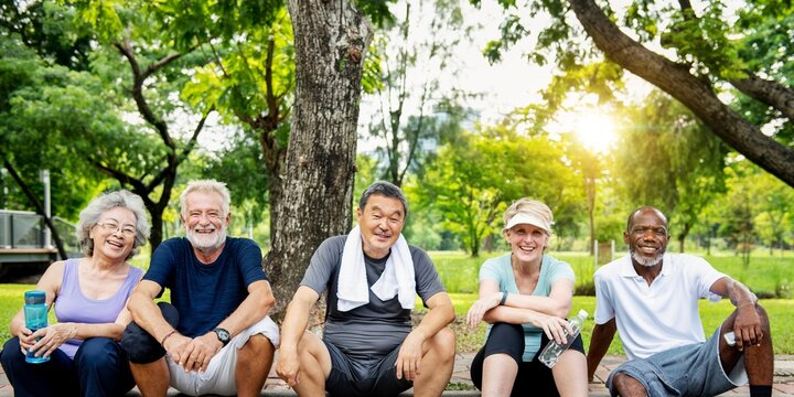 Group of diverse happy senior friends sit outdoors park. Diverse senior friends enjoy nature after park healthy exercise. Happy and healthy seniors, active outdoors lifestyle, diverse senior group