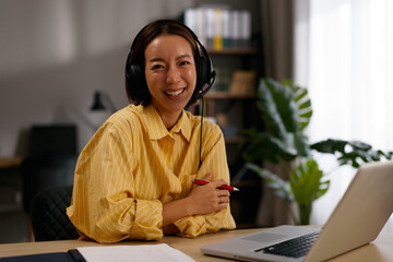 Young korean woman smiling while having an online video conference from her home office