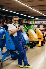 Construction worker using smartphone leaning on concrete mixer