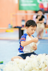 Seven-year-old Asian boy sitting on an indoor court floor and organizing shuttlecocks