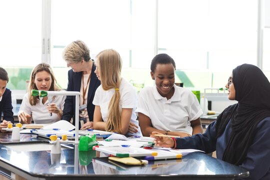 Diverse students in a science class, working together at a lab table. Engaged in experiments, the group includes both male and female students in bright classroom. Diverse students in lab, education.