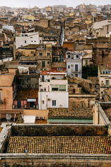 Panoramic View Over Ragusa From Cathedral Of San Giovanni Battista: Historic Sicilian City Rooftops, Church Domes, And Dense Stone Architecture Under Overcast Sky