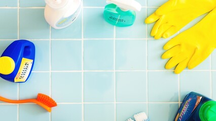 Cleaning supplies on blue tiles background. Cleaning gloves, cleaning brush, and cleaning sprays arranged neatly. Bright cleaning tools for effective cleaning. Cleaning supplies, pastel background.