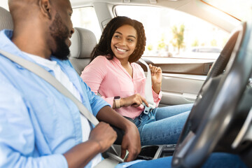 Safety First. Smiling African American Couple Fastening Seatbelts Before Driving In City, Sitting...