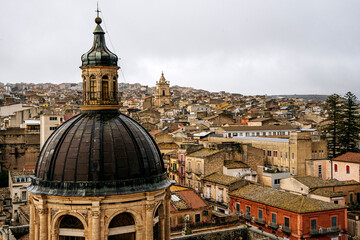 Panoramic View Over Ragusa From Cathedral Of San Giovanni Battista: Historic Sicilian City Rooftops, Church Domes, And Dense Stone Architecture Under Overcast Sky
