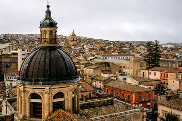 Panoramic View Over Ragusa From Cathedral Of San Giovanni Battista: Historic Sicilian City Rooftops, Church Domes, And Dense Stone Architecture Under Overcast Sky