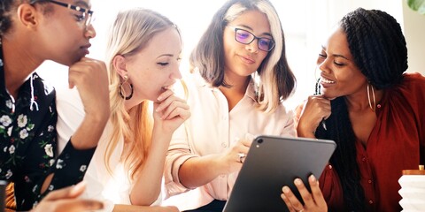 Four diverse business women collaborating in an office. Women working together, sharing ideas. Women in business attire, discussing projects. Professional business women. Diverse working woman.