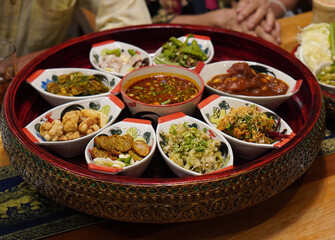 Thai food traditional, Khantoke dinner set, a classic Northern Thai (Lanna) dining, The food is presented on a large, ornate wooden tray on wooden table