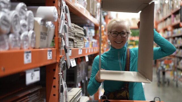 Mature woman shops for packing supplies to safely send family heirlooms while navigating aisles in a hardware store