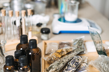 amber glass bottles and sachets of dried herbs on wooden tray with laboratory equipment in background. Phyto-cosmetics, active plant molecules, botanical engineering.
