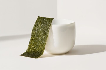 A quiet still life moment where crisp nori leans elegantly beside a minimalist white cup