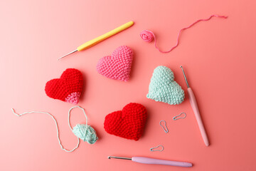 Valentines day crochet hearts decoration with tools on coral backdrop. Perfect for greeting cards retail marketing craft store advertising social media content festive seasonal sales promotion