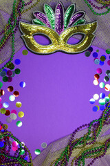 Festive Mardi Gras background with copy space, colorful beads and a sparkling mask.