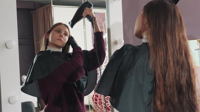 mirror view captures hairstyling process, stylist finishing touches as client observes in mirror, client observes hairstyle adjustments made by stylist during final blowdry session