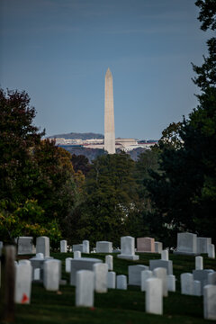 View of solemn rows of white headstones leading the eye toward the stark white Washington Monument piercing the horizon, Arlington, Virginia, United States.