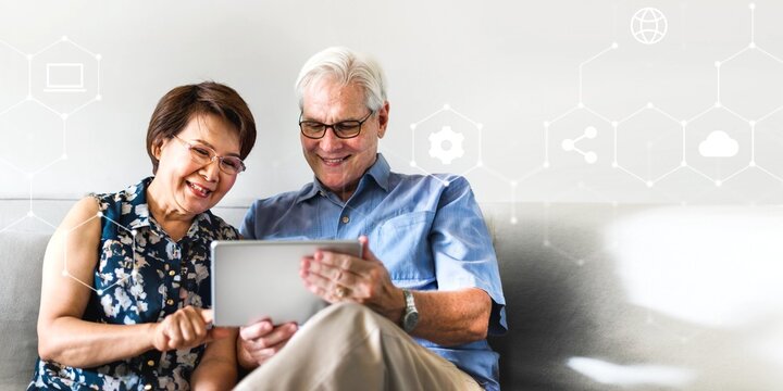 Senior couple using a digital device in a living room - Powered by Adobe