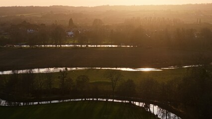 River Cherwell flowing through green fields and trees with sunlight reflecting on the water