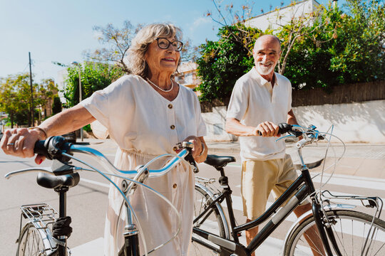 Happy senior couple walking bicycles enjoying active retirement