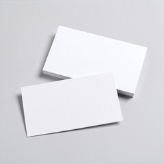 Two pristine, blank business cards lie side by side on a smooth white surface, showcasing their clean edges and minimalist design, ready for customization.