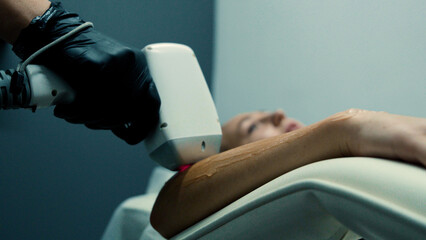 Cosmetologist in uniform working with laser hair removal machine.