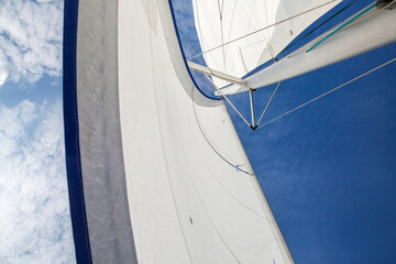 Fototapeta premium Blue and White Sailboat with Full Sails Against Sky