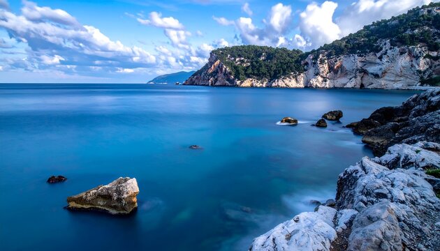 Scenic coastal view featuring rocky shoreline, calm turquoise waters, and distant cliffs under clouds - Powered by Adobe