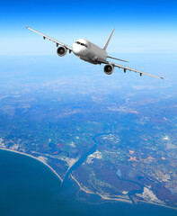 Naklejka premium Passenger jet flying above coastal river estuary
