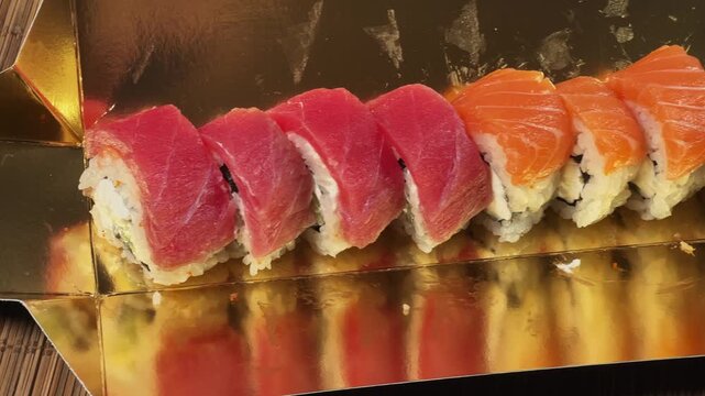 Sushi rolls uramaki with salmon and tuna in golden packaging