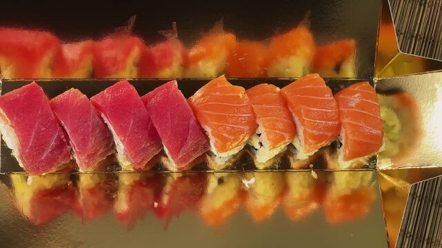 Sushi rolls uramaki with salmon and tuna in golden packaging