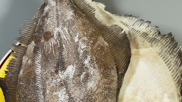 Two raw frozen flounders on a big yellow plate
