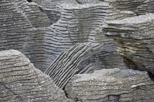 View of layered limestone formations sculpted by nature's hand stand as silent sentinels in a rugged, otherworldly landscape, Punakaiki, West Coast Region, New Zealand.