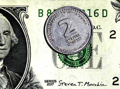 Israeli 2 shekel coin on US dollar banknote background, close-up concept of currency exchange, finance, and international economy.