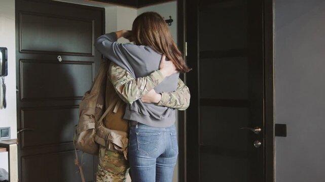 A soldier leaves home for duty and hugs his wife goodbye in the hallway. She misses him and cries on the floor near the door.