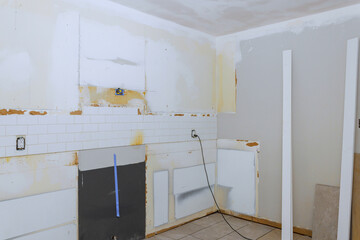 Kitchen undergoing renovation bare walls, missing tiles, unfinished surfaces, ready for updates.