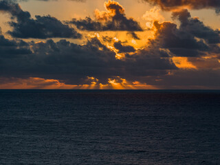 Golden light pierces storm clouds over the Atlantic off Fuerteventura, Canary Islands, illuminating dark indigo sea as day yields to night with layered formations.