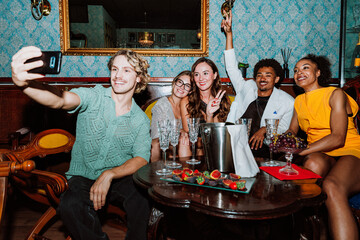 Diverse friends taking selfie celebrating party with champagne